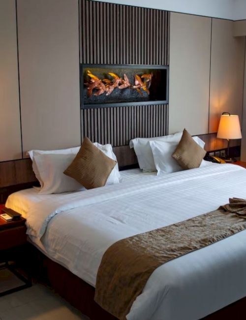 A hotel room with a neatly made double bed, two bedside tables with lamps, and a wall decoration above the bed.