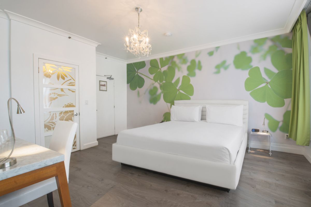 A white bedroom with a large bed, a desk, and a chandelier