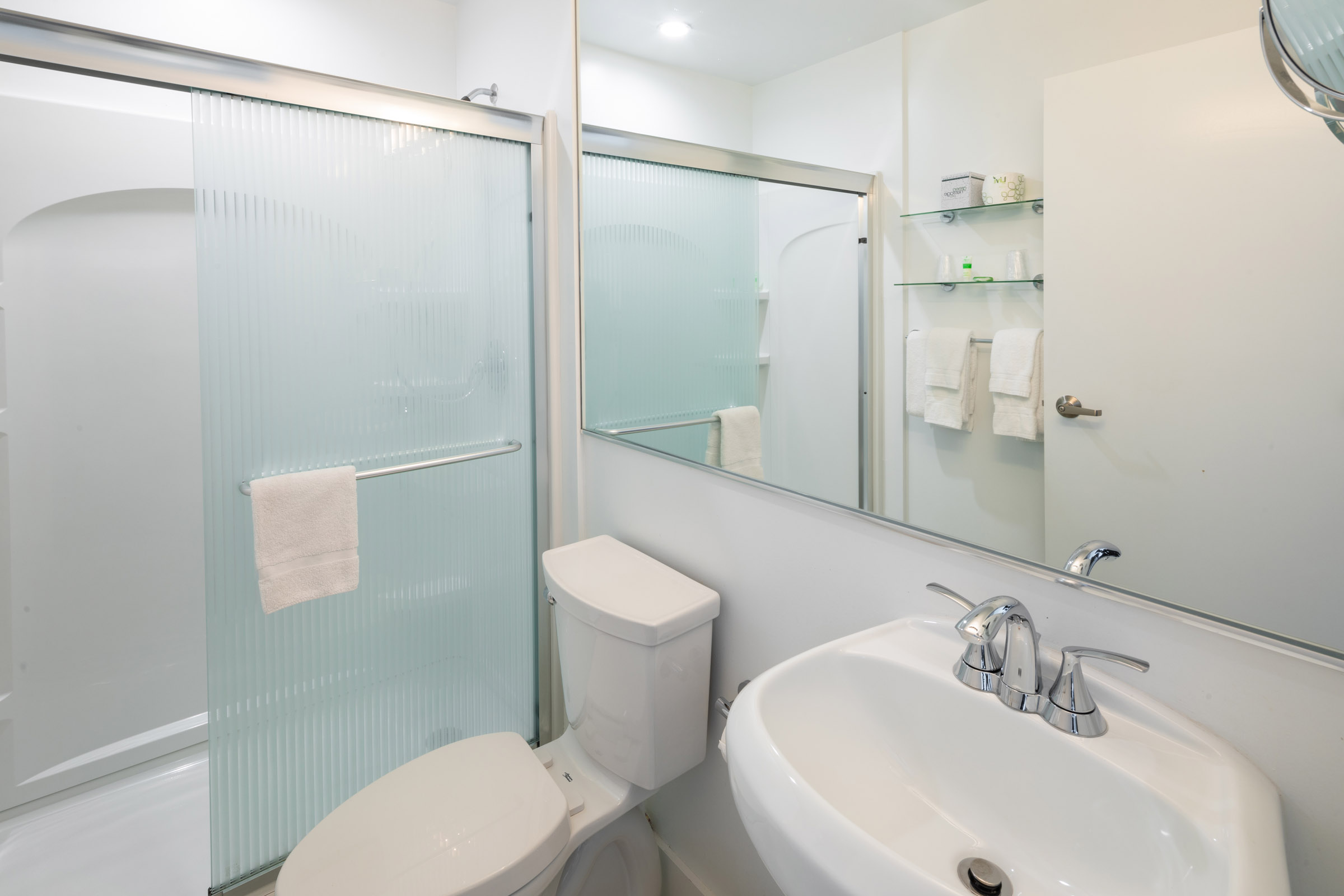 A clean and modern bathroom with a toilet, shower, and sink