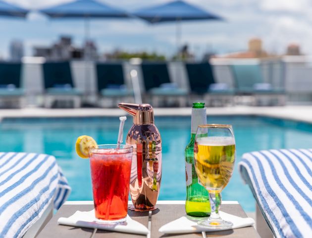a table with drinks and towels by the pool