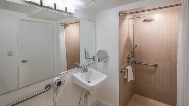 A bathroom with a sink, mirror, and shower