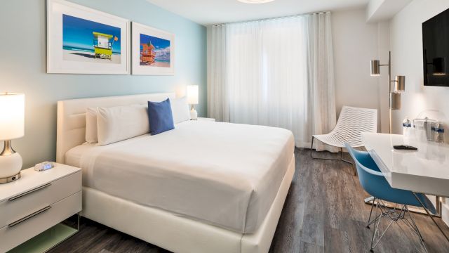 A wide view of a hotel room with a large bed, desk, and chair.
