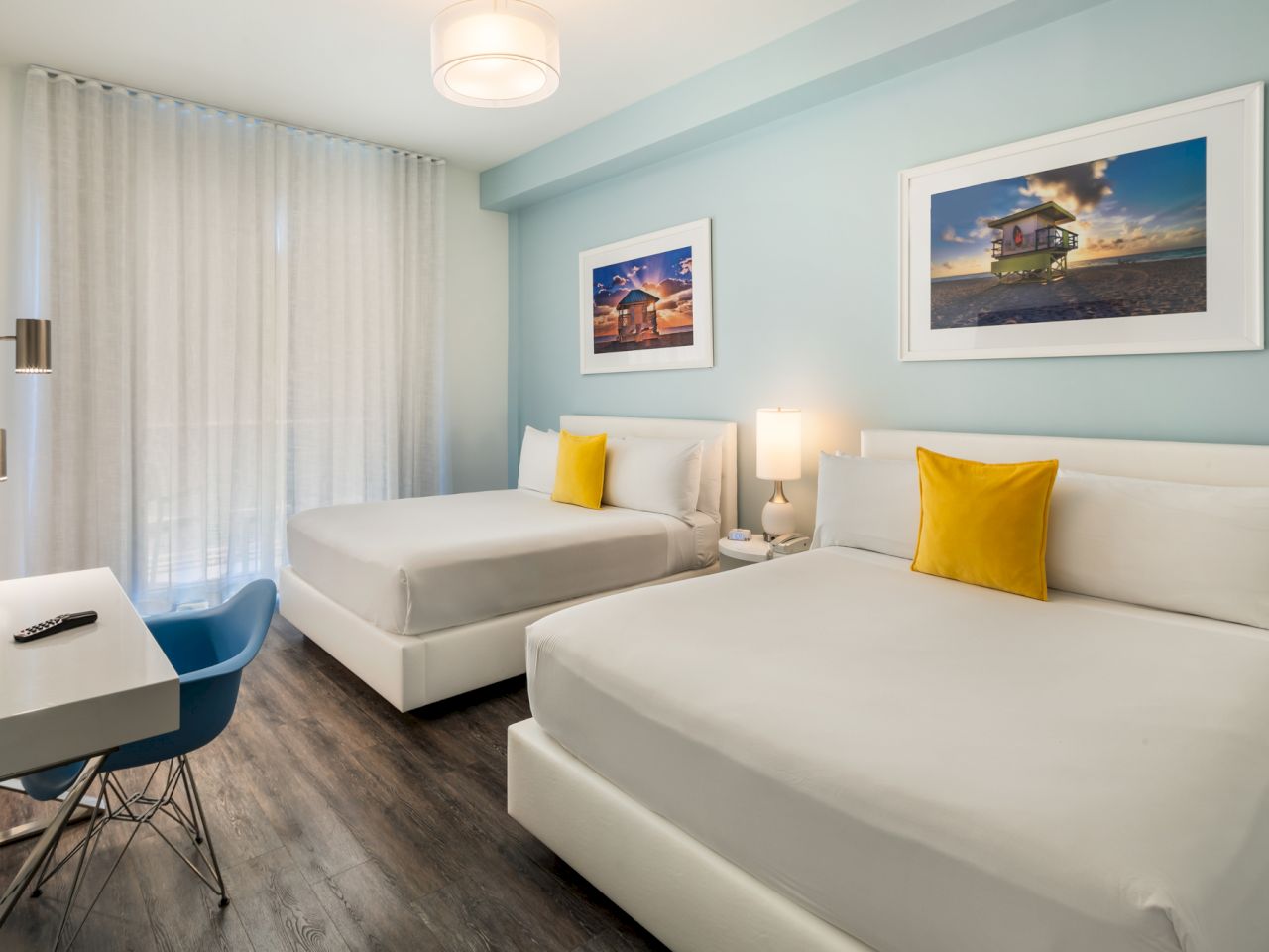 A hotel room with two beds, a desk, and a chair.