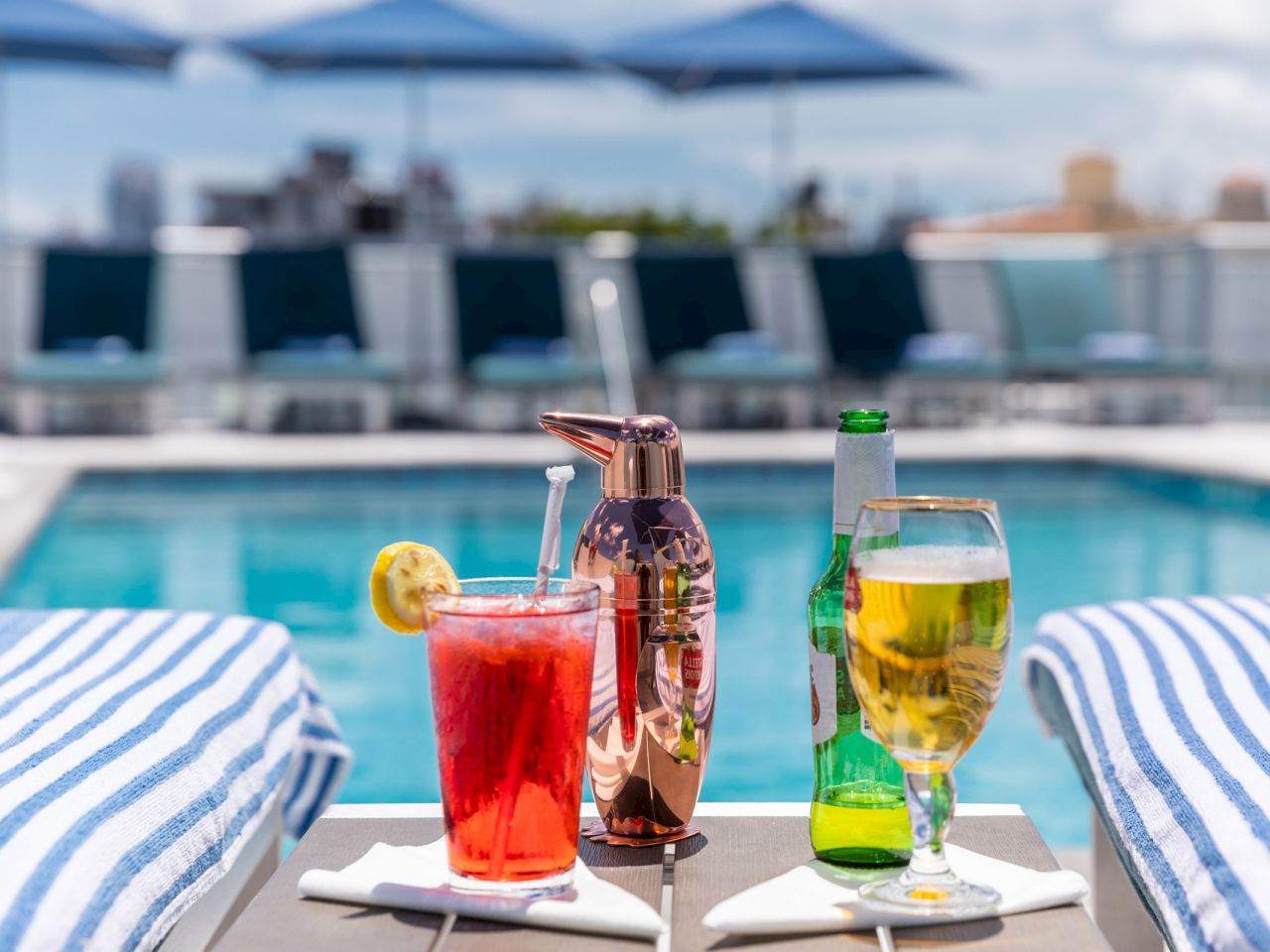 A table with drinks and towels by the pool.