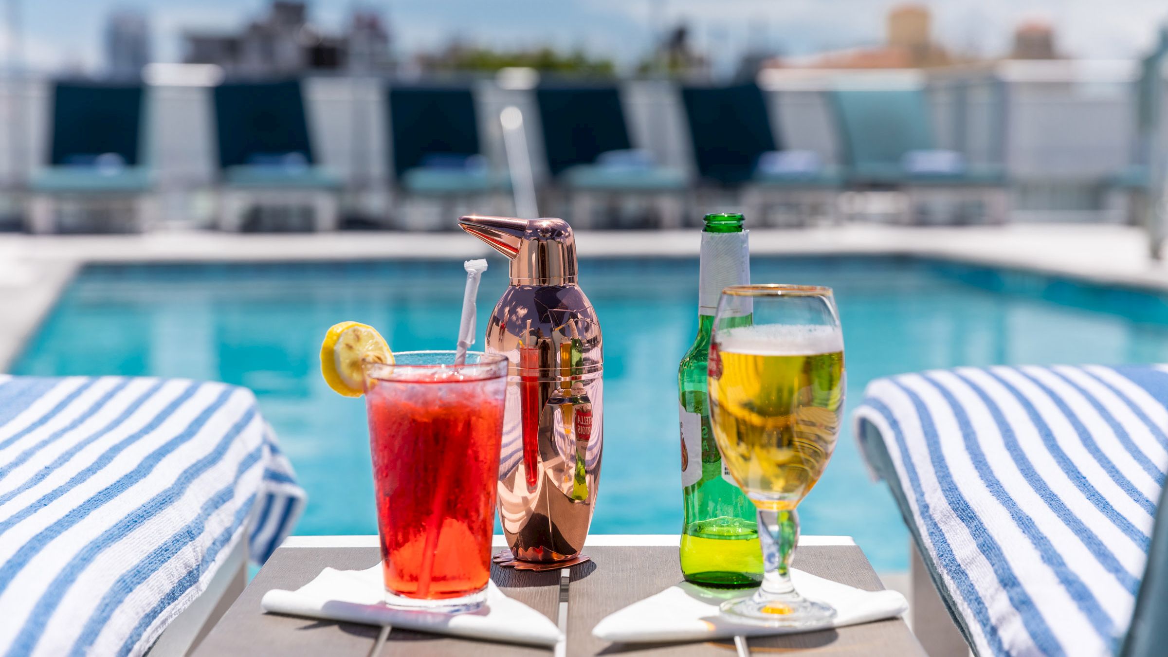 A poolside setup with drinks and towels on lounge chairs.