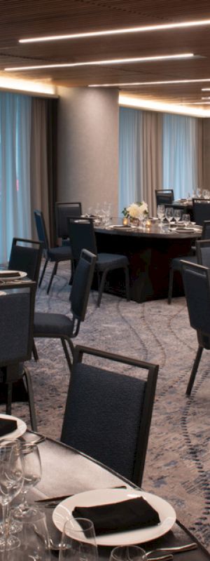 The image shows an elegantly set banquet hall with round tables, chairs, and decorative place settings, ready for an event.