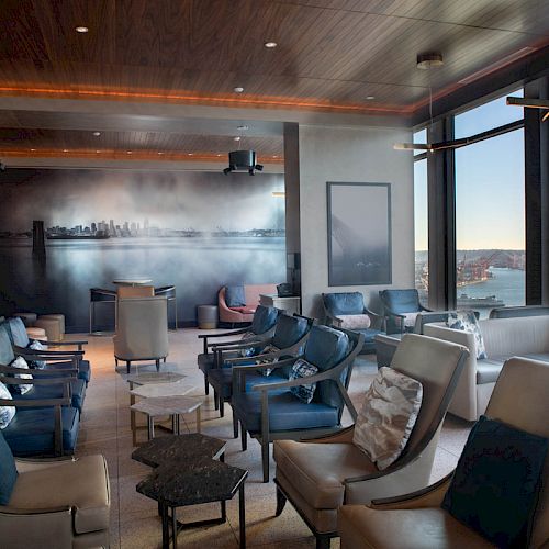 A spacious lounge with modern seating, large windows offering a waterfront view, and soft lighting, creating a tranquil atmosphere.